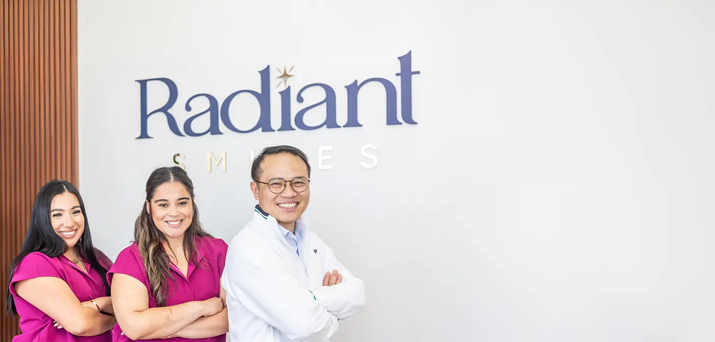Dental team members smiling in front of wall with arms folded
