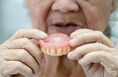Senior placing a denture in their mouth