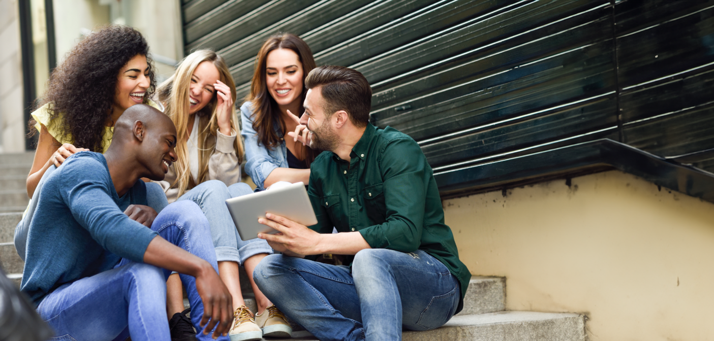 Group of young adults sitting at the bottom of a staircase and laughing together after receiving dental services in Grand Prairie