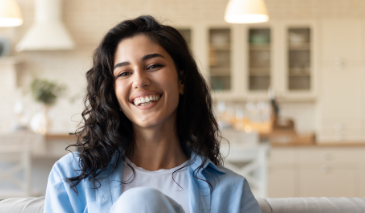 Woman with wavy dark hair smiling at home