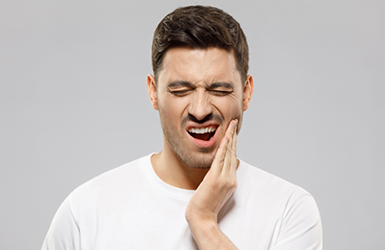 Woman touching his cheek and wincing in pain