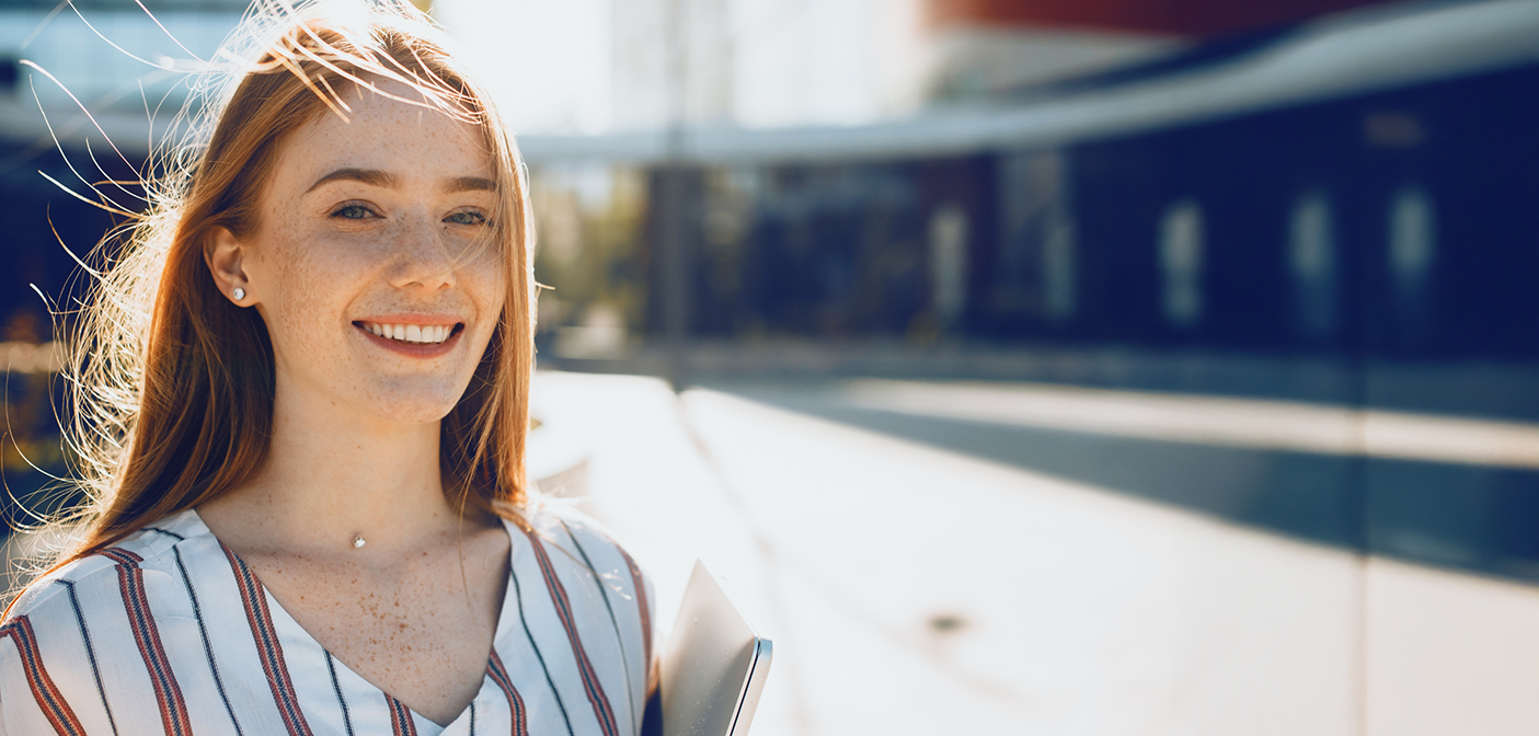 Young redheaded woman smiling in the sun after restorative dentistry in Grand Prairie