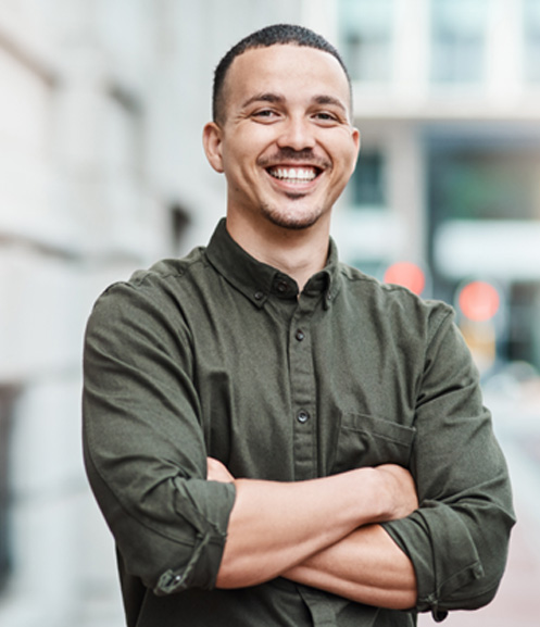 Man standing outside building smiling with arms folded