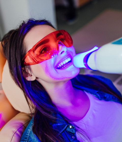 Woman sitting in dental chair receiving teeth whitening in Grand Prairie